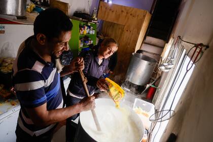José Luis Medina, el cocinero, y una colaboradora preparan la comida en las ollas de 150 litros. 