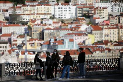 Jóvenes con mascarillas conversan en un mirador sobre el centro histórico de Lisboa (AP Foto/Armando Franca)