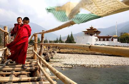 Jóvenes monjes cruzan el puente de madera y bambú que va desde el Dzong hasta el pueblo de Punakha, al otro lado del río.