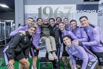 Juan Carlos Rulli, gloria de la Academia, a upa de Gustavo Costas, en su visita al plantel de Racing
