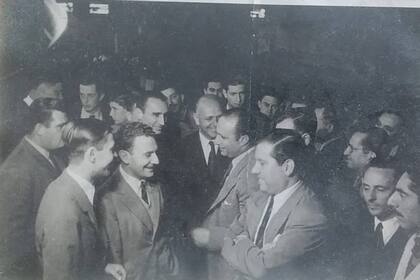 Juan Manuel Fangio visita Hafdasa y sonríe con los Ballester Molina, Carlos padre y Carlos hijo