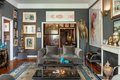 Juego de sofás de Nosten, diseñados por Cristián Mohaded; conjunto de obras en papel de grandes maestros del siglo XX junto a artistas contemporáneos argentinos; y sobre la chimenea, una colección de antiguas piezas francesas en porcelana.