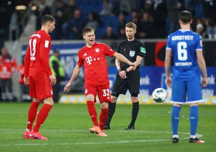 Jugadores del Bayern Munich y el Hoffenheim se pasan la pelota ante la impávida mirada del árbitro; un polémico partido reciente en la Bundesliga