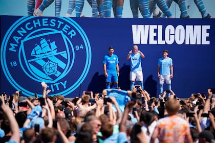 Julián Álvarez, derecha, Erling Haaland, centro, y Stefan Ortega Moreno son vitoreados por los fanáticos del Manchester City durante la presentación de los refuerzos del equipo de la Liga Premier, en Manchester, Inglaterra, el domingo 10 de julio de 2022. (AP Foto/Dave Thompson)