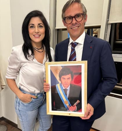 Juliana Santillán, diputada de la Nación por La Libertad Avanza. junto a Foster Gillett, que sostiene un retrato de Javier Milei, promotor central del ingreso de las SAD al fútbol argentino