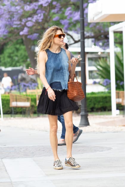 Julieta Kemble, con top de jean, mini, cartera de fibras naturales y zapatillas con estampa animal