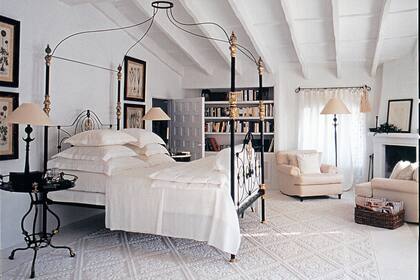 Cama y mesa de luz victoriana. La espectacular alfombra de lana blanca fue tejida a mano en Cerdeña. Todas las lámparas tienen diseño de Giacometti.
