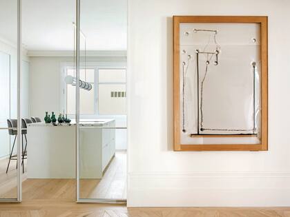 Junto a la entrada con puertas de vidrio corredizas, que establecen un límite entre el parquet y el entablonado, cuadro enmarcado en madera lavada de Jordi Alcaraz.