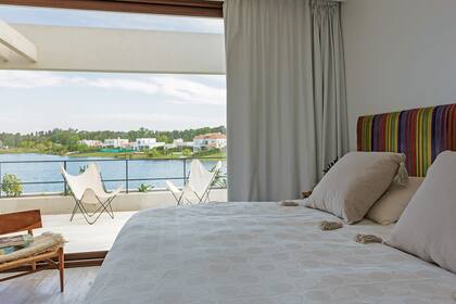 Junto a la ventana de la suite, silla ‘Ska’ (Net Muebles) con manta (Madison Market). Mesas de luz (Pasto Home Deco) y almohadones con borlas (Madison Market).