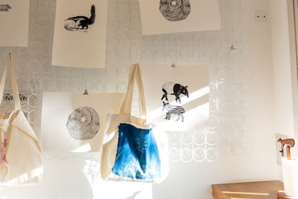 Junto a la ventana, objetos expuestos sobre el mismo sistema de resorte de colcón que tiene en su taller. Los bolsos de tela están estampados con técnicas de serigrafía y de cianotipo y son los que más vendidos en el local.
