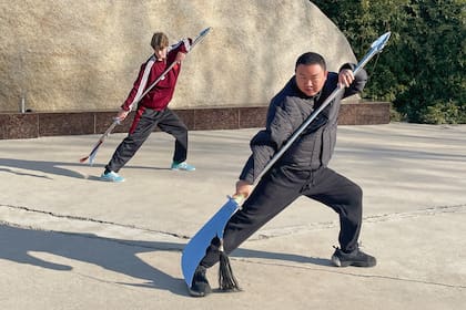 Junto a un instructor en una demostración de dominio de otra de las armas del kung-fu, la espada guadao, conocida como “hoja del dragón verde”