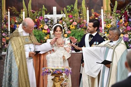 Junto al obispo Johan Dalman y el párroco de la Royal Court Parish, Michael Bjerkhagenen, en plena ceremonia. Se derramó sobre el bebé agua de una fuente de Öland, una tradición que comenzó en la familia real sueca con el bautismo de la princesa Victoria, heredera del trono.