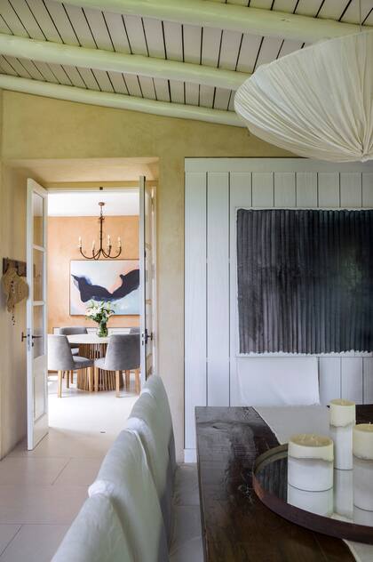 Junto al ventanal con cortinas de gasa pañalera (Tapicenter), mesa hecha a medida, con objetos de centro comprados en anticuarios, al igual que la lámpara de seda plisada.