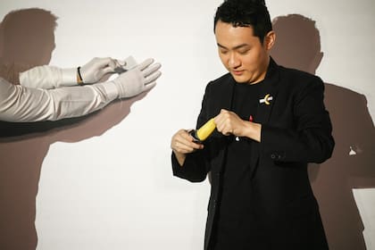 Justin Sun se prepara para comerse una "obra de arte" compuesta por una banana pegado a una pared con cinta adhesiva, hoy en Hong Kong