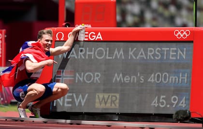 Karsten Warholm, de Noruega, celebra junto al marcador que muestra su récord mundial al ganar la medalla de oro en la final de los 400 metros con vallas masculinas.