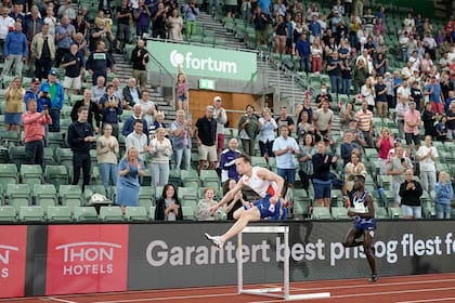 Karsten Warholm, en pleno salto durante los 400 metros con vallas; lo sigue el brasileño Alison Dos Santos