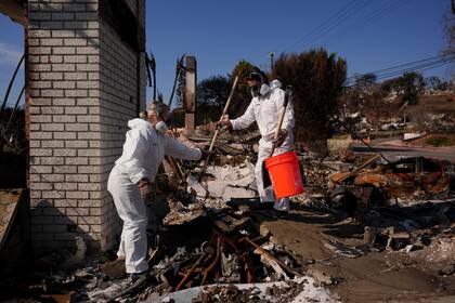 Katelyn White, a la izquierda, y su marido John Borbone revisan su propiedad devastada por el fuego tras el incendio de Palisades, en el barrio de Pacific Palisades de Los Ángeles, el martes 28 de enero de 2025. (AP foto/Jae C. Hong)