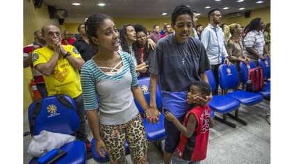 Katia Maria Soares, su compañera Carolina y su hijo participan en el servicio dominical