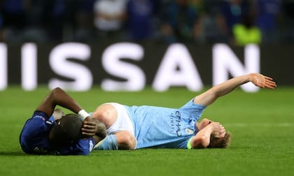 Kevin De Bruyne pide asistencia luego de golpearse contra Antonio Rudiger, quien también está en el piso.