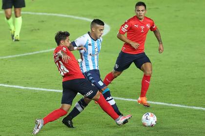 Kevin Gutiérrez, mediocampista central de Racing, maniobra ante dos futbolistas de Independiente. 