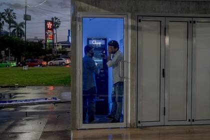 Kevin Martinez, de 26 años, a la izquierda, y Harold Valle, de 32 años, intentan enviar dinero a través de un cajero automático Chivo en San Salvador