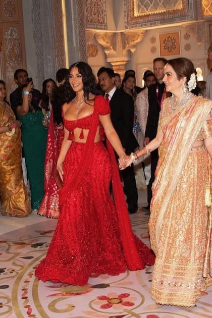 Kim Kardashian
–con un total look
en rojo, bordado
en piedras,
formado por un
microtop con
borlas y una falda
larga con cola–
camina de la
mano de la madre
del novio, Nita.
Para completar,
llevó varios
collares de
diamantes.