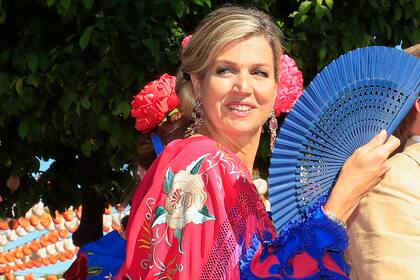 Máxima eligió un vestido flamenco azul royal blue con mantón fucsia y flor haciendo juego en el pelo, recogido como manda la tradición. 