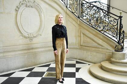 Kirsten Dunst también optó por un outfit sobrio pero no menos elegante para el desfile de Dior: su conjunto de pantalón de gamuza beige y blusa negra con volados en su delantera sorprendió por un accesorio que es última moda, los tiradores