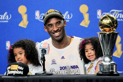 Kobe Bryant de Los Angeles Lakers sonríe con sus hijas Gianna y Natalia con el Trofeo Bill Russell MVP después de que su equipo derrotó a los Boston Celtics