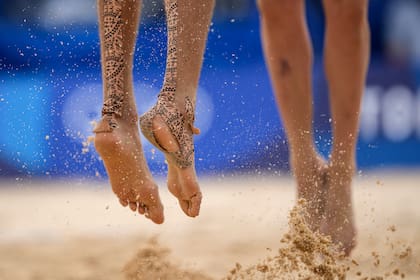 Konstantin Semenov, a la izquierda, del Comité Olímpico Ruso, con cinta en los pies salta durante un partido de voleibol de playa masculino contra Australia en los Juegos Olímpicos de Verano de 2020, el lunes 26 de julio de 2021, en Tokio, Japón.