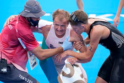 Kristian Blummenfelt recibe ayuda después de ganar la medalla de oro durante el triatlón individual masculino en los Juegos Olímpicos; el calor fue agobiante