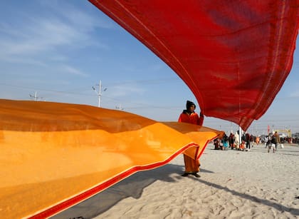 Un hombre seca saris después de tomar un baño durante el primer "Shahi Snan" (el gran baño) en "Kumbh Mela"