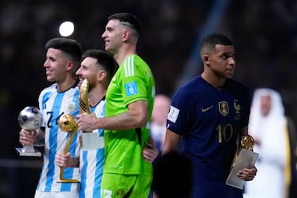 Kylian Mbappé (derecha) se marcha con su Botín de Oro, mientras posan con sus trofeos, de izquierda a derecha, los argentinos Enzo Fernández, Lionel Messi y Emiliano Martínez, luego de la final mundialista del domingo 18 de diciembre de 2022, en Lusail, Qatar