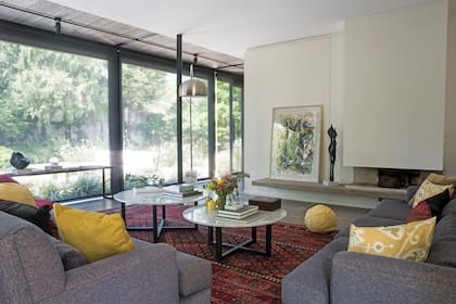 La abertura de PVC avanzó sobre el jardín ampliando el espacio interior e incorporando las delgadas columnas negras. Esculturas en bronce, de Elisa Bunge, y cuadro de Rodrigo García Berro.