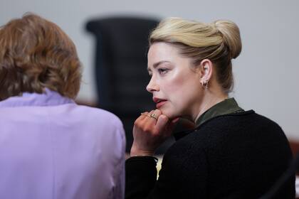 La actriz Amber Heard habla con una miembro de su equipo legal en el Tribunal de Circuito del Condado de Fairfax, en Fairfax, Virginia (Evelyn Hockstein/Pool photo via AP)
