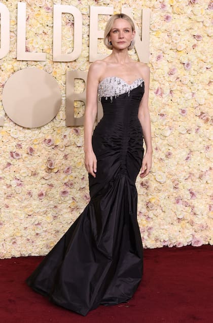 La actriz Carey Mulligan combinó el negro con los brillos para su look: un vestido largo negro con un toque de color en el escote y apliques 