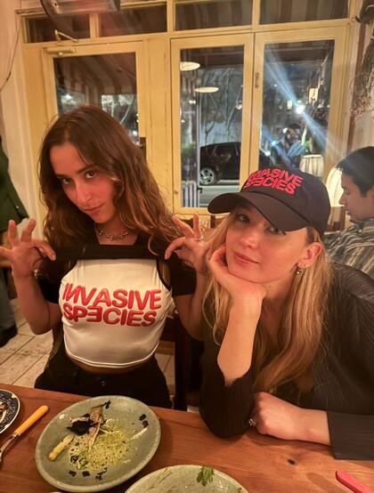 La actriz Jennifer Lawrence con la gorra de la obra de teatro de la argentina Maia Novi, Invasive Species, junto con la artista plástica canadiense Chloe Wise
