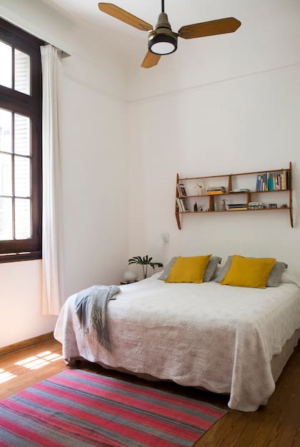 La alfombra al pie de la cama es un aguayo comprado en Salta; la estantería de los años 50, un hallazgo de un anticuario. Almohadones (Ikea).