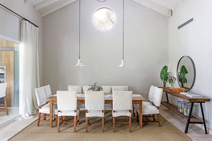 A una mesa que tenían le sumaron sillas con tapizado de lino y terciopelo blanco; en uno de los laterales, un banco de cuatro puestos renovado con lino de arpillera de algodón (todo de 11.11 Home Deco). La alfombra es un diseño especial de Rugit para 11.11 Home Deco.