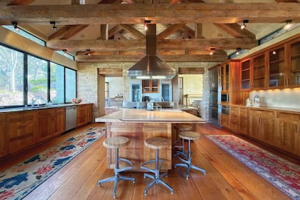 La amplia cocina es fiel al estilo de toda la propiedad: ventanas de estilo industrial que contrastan con las paredes revestidas en piedra y las vigas de madera a la vista