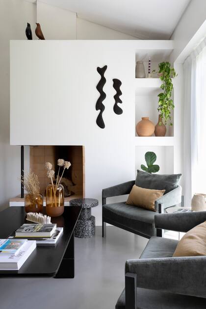La arquitecta Sara Plazibat cerró el frente de la chimenea para colgar la obra en madera de kiri de Agustín Leiro y crear nichos para objetos decorativos, como los jarrones de arcilla (Philippa Deco Boutique).