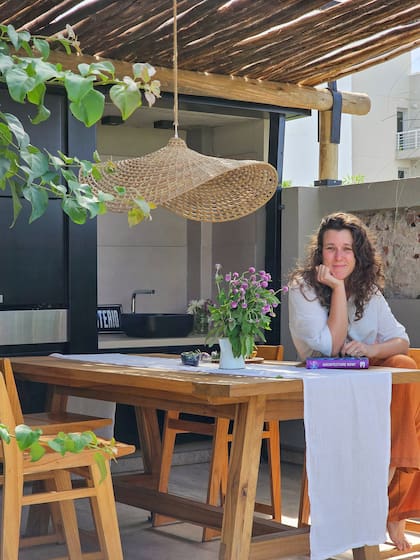 La arquitecta y dueña de casa en su terraza. Mesa (Místico muebles), sillas (Unimate). Artefacto de iluminación (La Chicha Store). La pérgola con troncos de eucaliptos y el frente de parrilla, en chapa plegada, son diseño de Yael.