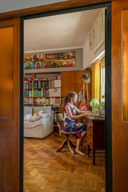 La artista en su escritorio, parte de la planta que reserva para su uso personal. Como da a la calle, los vecinos se asoman a saludar o traerle un regalo a Walter, que acompaña a su mamá por todas las plantas a lo largo del día.