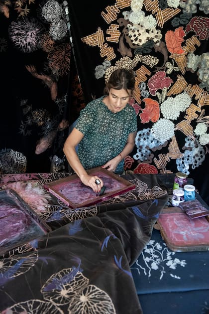 La artista trabajando en el taller. Detrás de ella, su obra expuesta en el Museo Nacional del Traje, en el marco de ‘Teleteca’, Bienal Sur, 2023