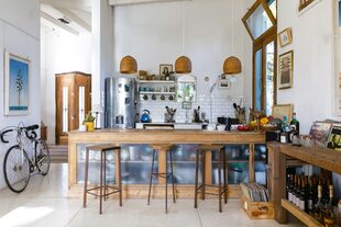 La barra de madera y vidrio esmerilado limita la cocina, ofrece espacio de guardado y es comedor, gracias a las tres banquetas de hierro y madera (Bobby Rastalsky).