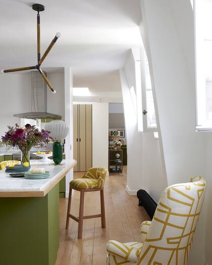 La base de la isla, un lugar pocas veces pensado para dar color, acá en un verde que se lleva bien con el piso y con las banquetas tapizadas. Al fondo, la conexión con el living que vemos abajo.