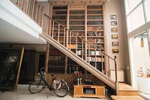 La biblioteca de esta casa ocupa toda la pared y está cruzada por la escalera que va a las habitaciones del primer piso y permite llegar a los libros más altos en su recorrido