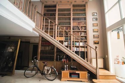 La biblioteca de esta casa ocupa toda la pared y está cruzada por la escalera que va a las habitaciones del primer piso y permite llegar a los libros más altos en su recorrido