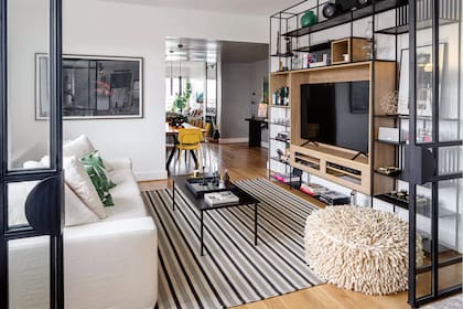 La biblioteca de hierro y roble (Studio VS) aloja una gran TV y varios de los objetos favoritos de los dueños de casa. Obra enmarcada de Viviana Blanco.