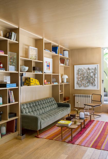 La biblioteca, que ocupa la antigua zona de servicio, está íntegramente enchapada en pino Hemlock. Sillón (Ohmio Gallery), silla ‘Cesca’ y mesitas bajas (Walmer). Junto a la obra en papel plisado de Leticia Gelosi, se asoma la escalera exterior.